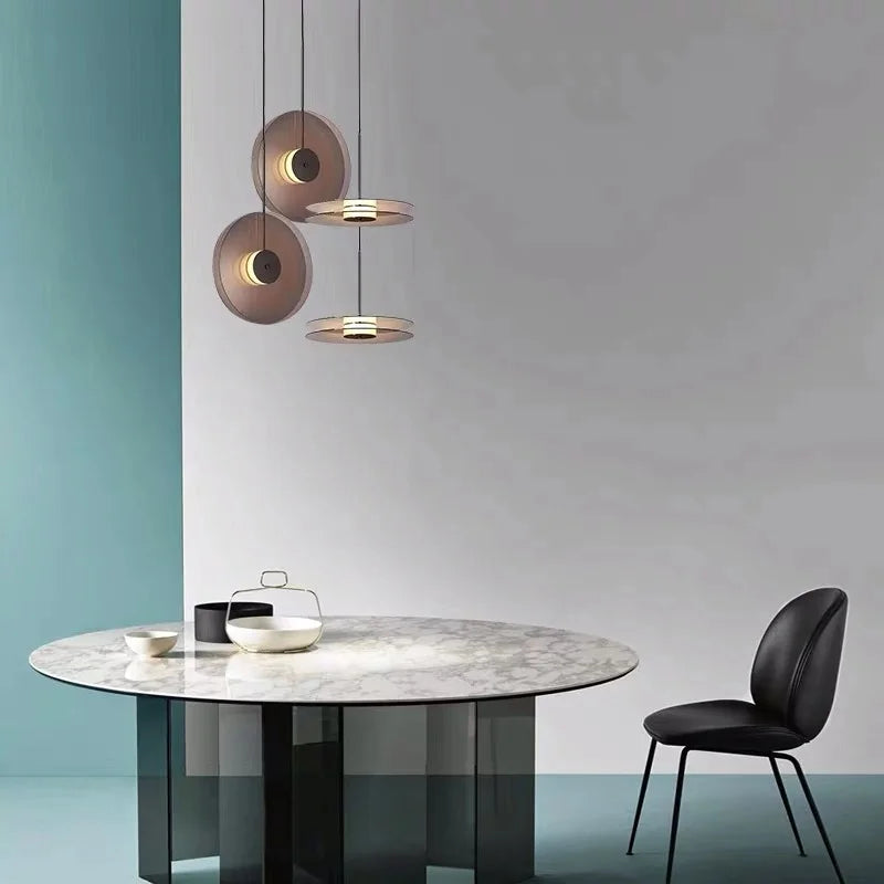Modern dining table with marble top and black chair, featuring three hanging pendant lights.