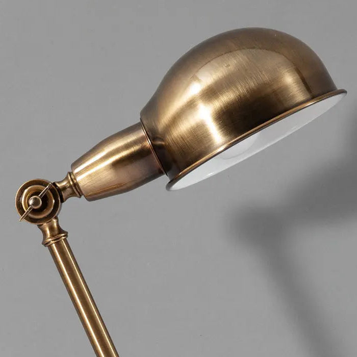 Brass floor lamp with adjustable arm on a gray background