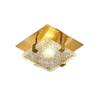 A modern square ceiling light fixture with a textured clear glass shade and a brushed gold metal frame, shown illuminated against a neutral background.