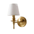 Wall-mounted lamp with white shade and gold fixture on a white wall