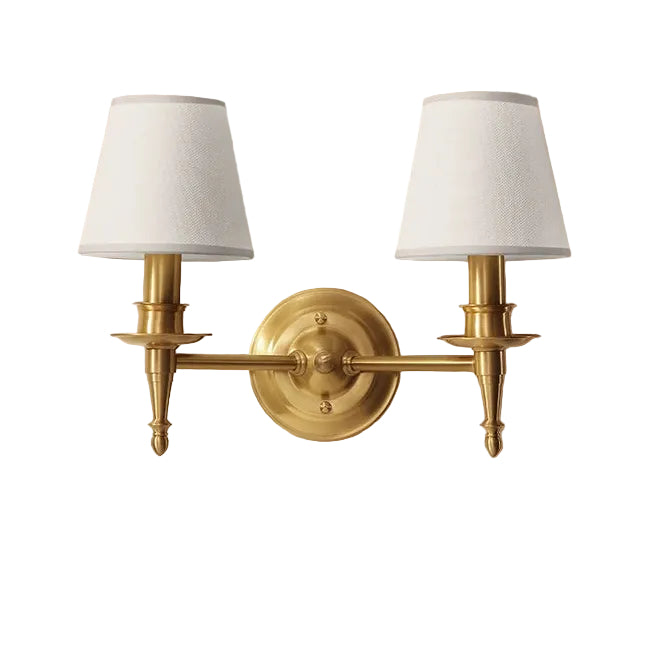 Gold wall sconces with white lampshades on a beige wall.