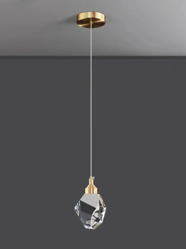 Pendant light with crystal shade and gold fixture on a gray background