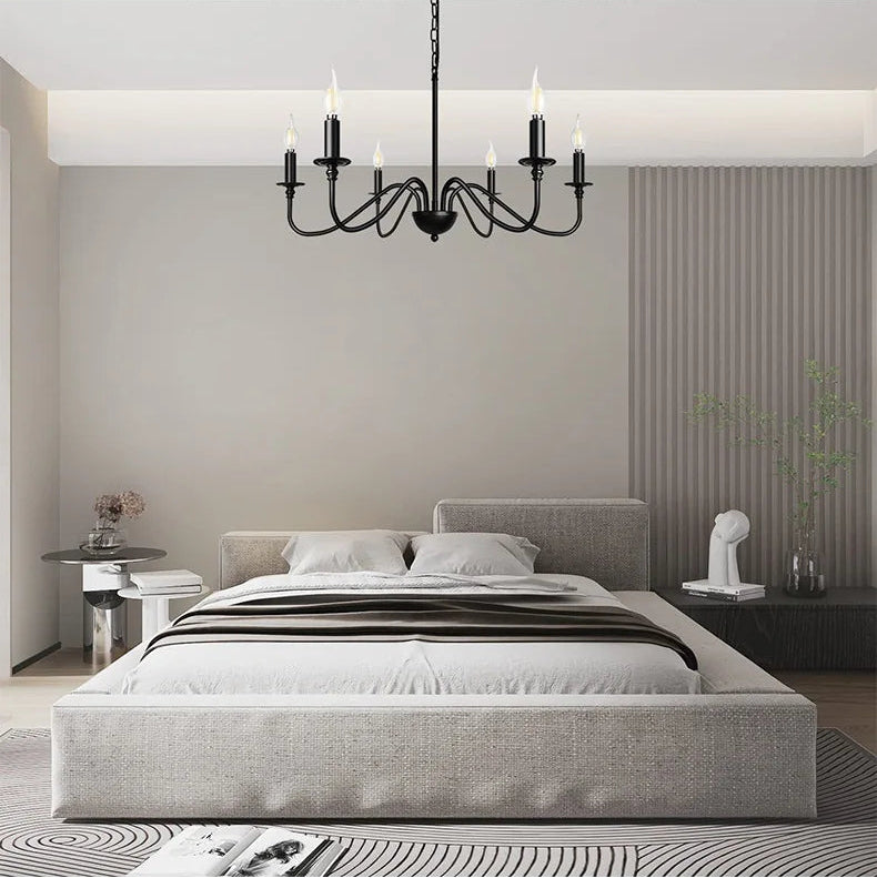 Modern bedroom with gray bed and chandelier, transitioning to a dining area with white table and chairs.