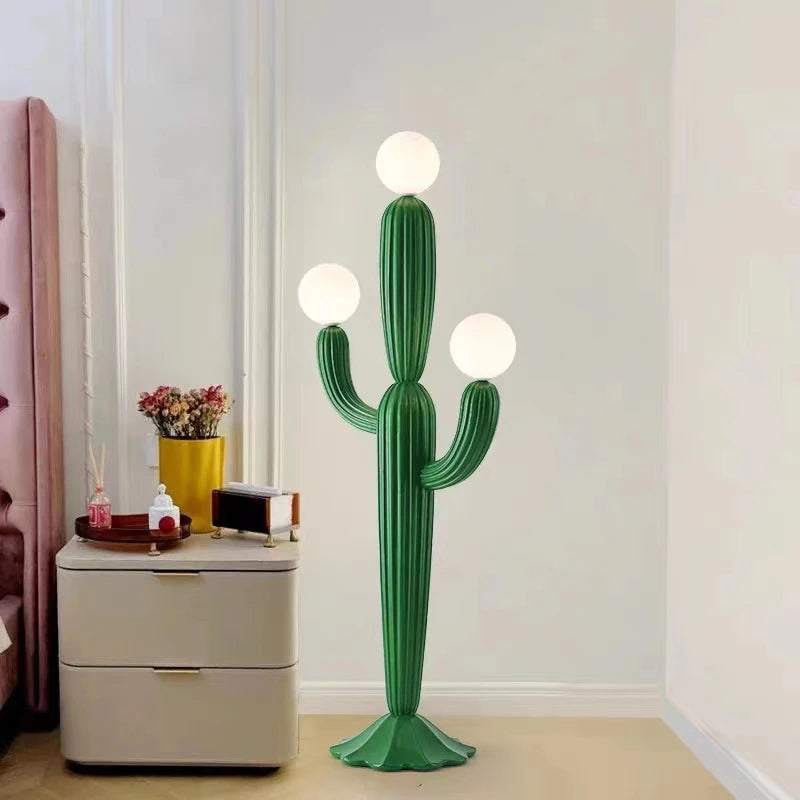 Cactus-shaped floor lamp in a room with a nightstand and decorative items.