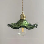 Green glass pendant light with brass fixture on a plain background