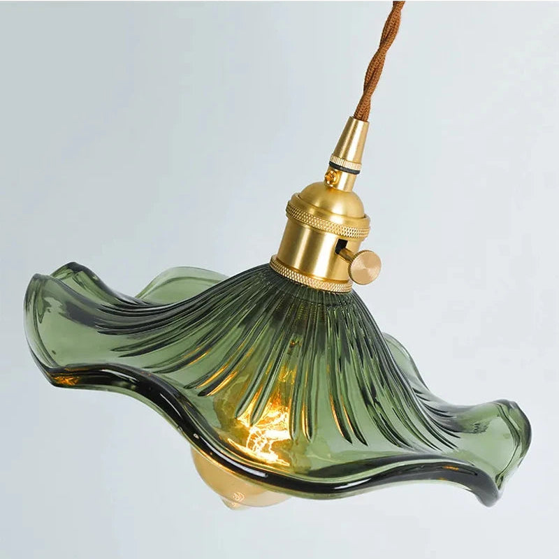 Green glass pendant light with gold fixture on a light gray background
